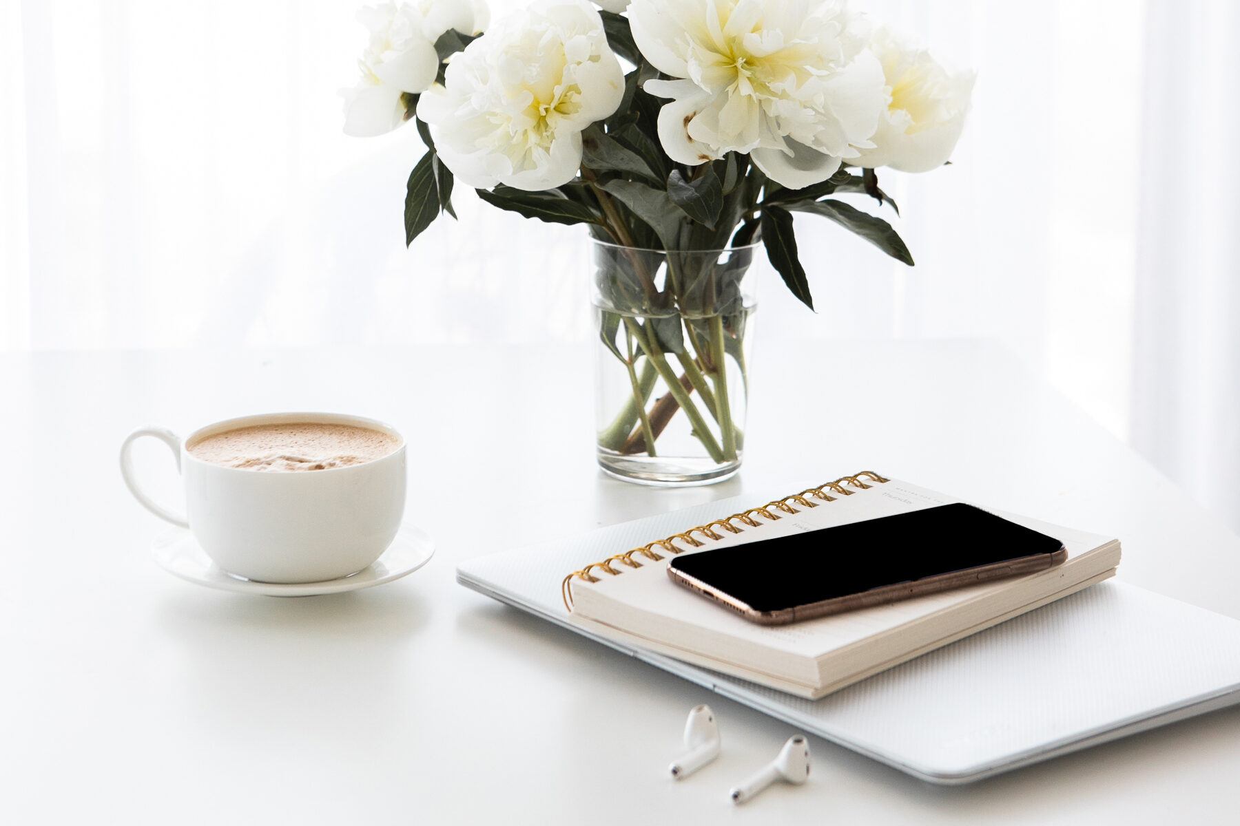 laptop, notebook, phone, cup of coffee, and white flowers | Carlisle & Co. digital marketing agency