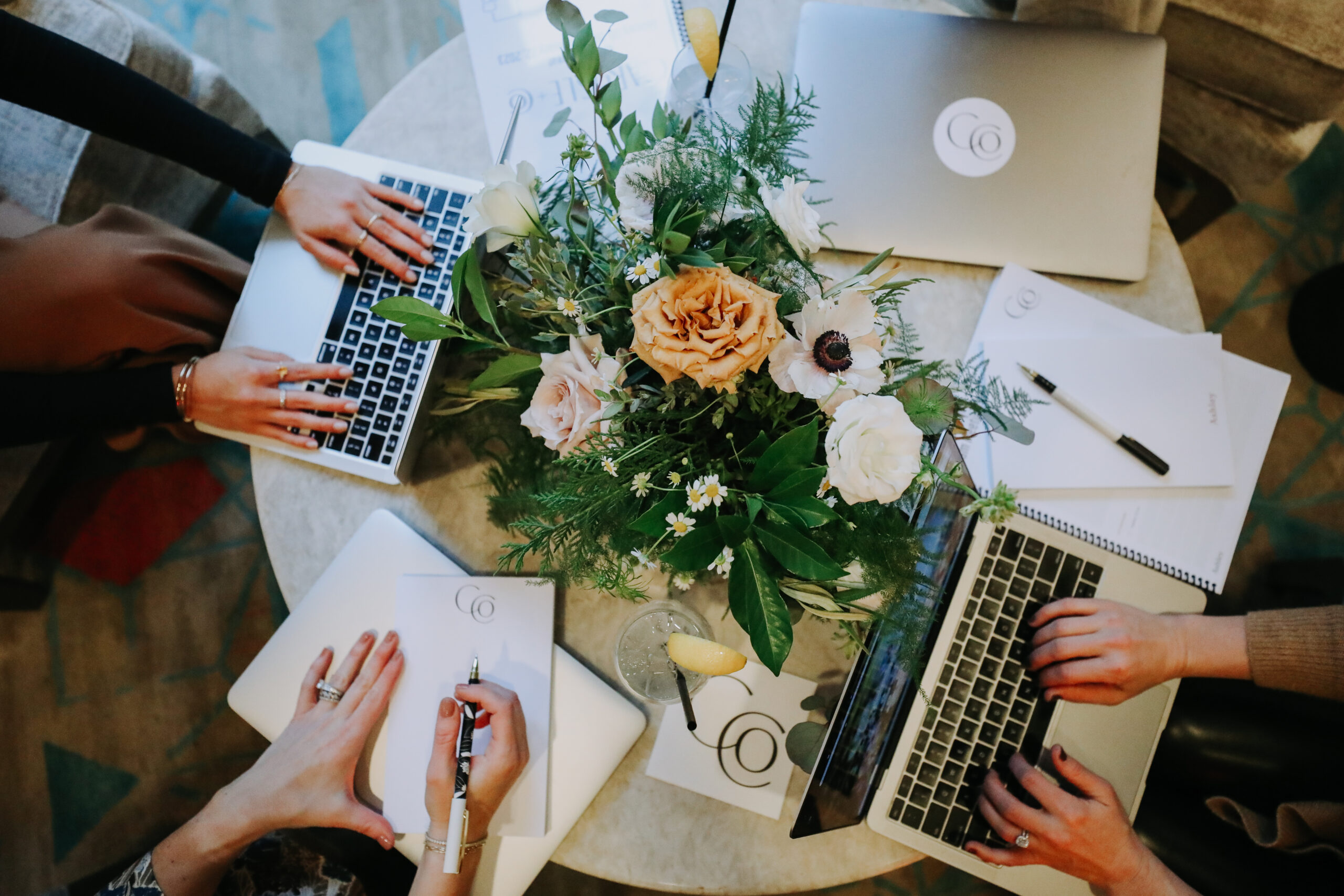 flowers and laptops on a table with women working | Carlisle & Co. digital marketing agency