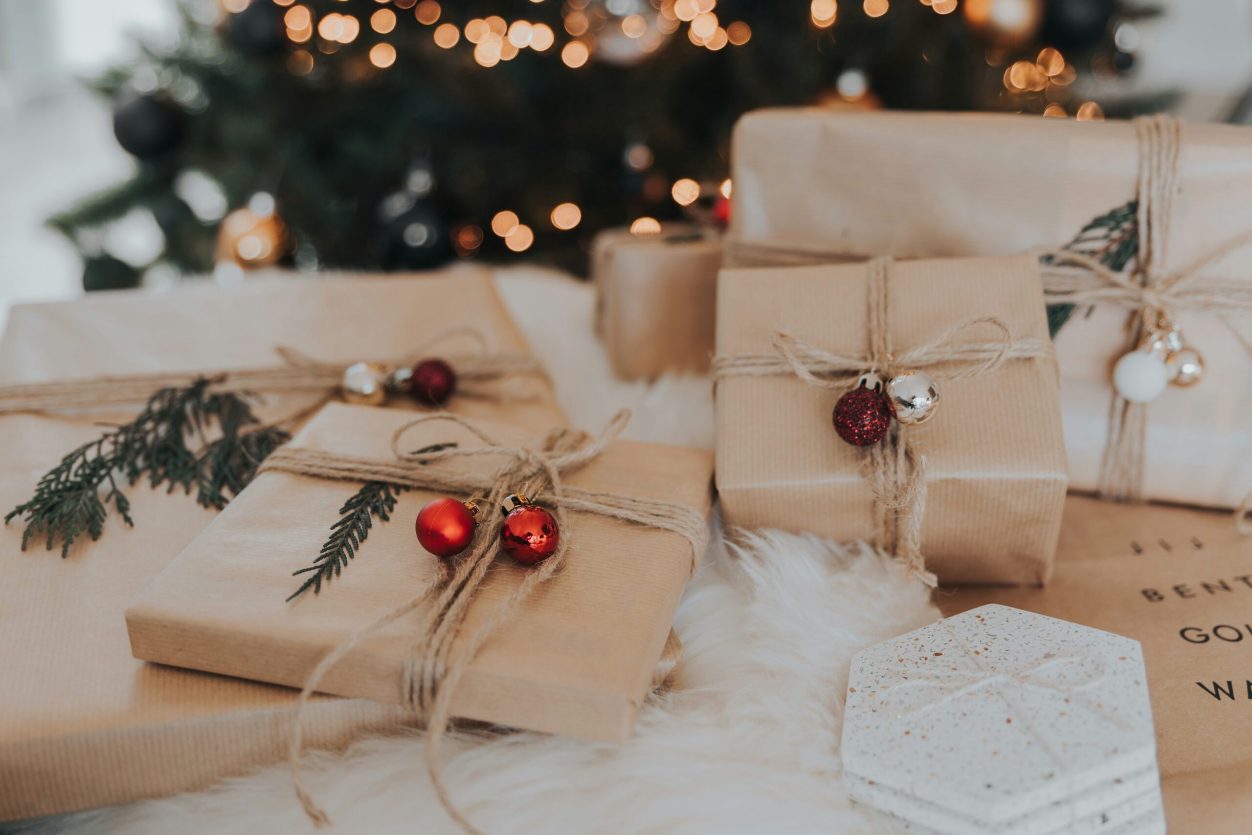 holiday gifts wrapped in kraft paper with twine and red bells | carlisledigitalmarketing.com