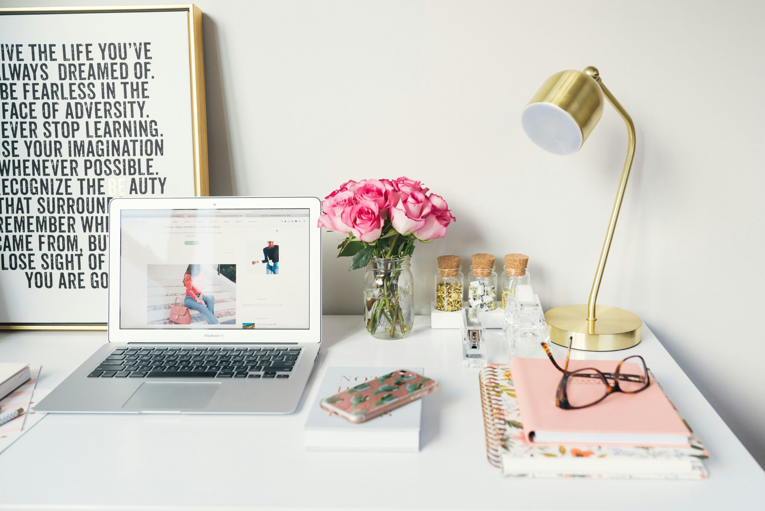 feminine desk with laptop, gold lamp, and pink flowers | carlisledigitalmarketing.com