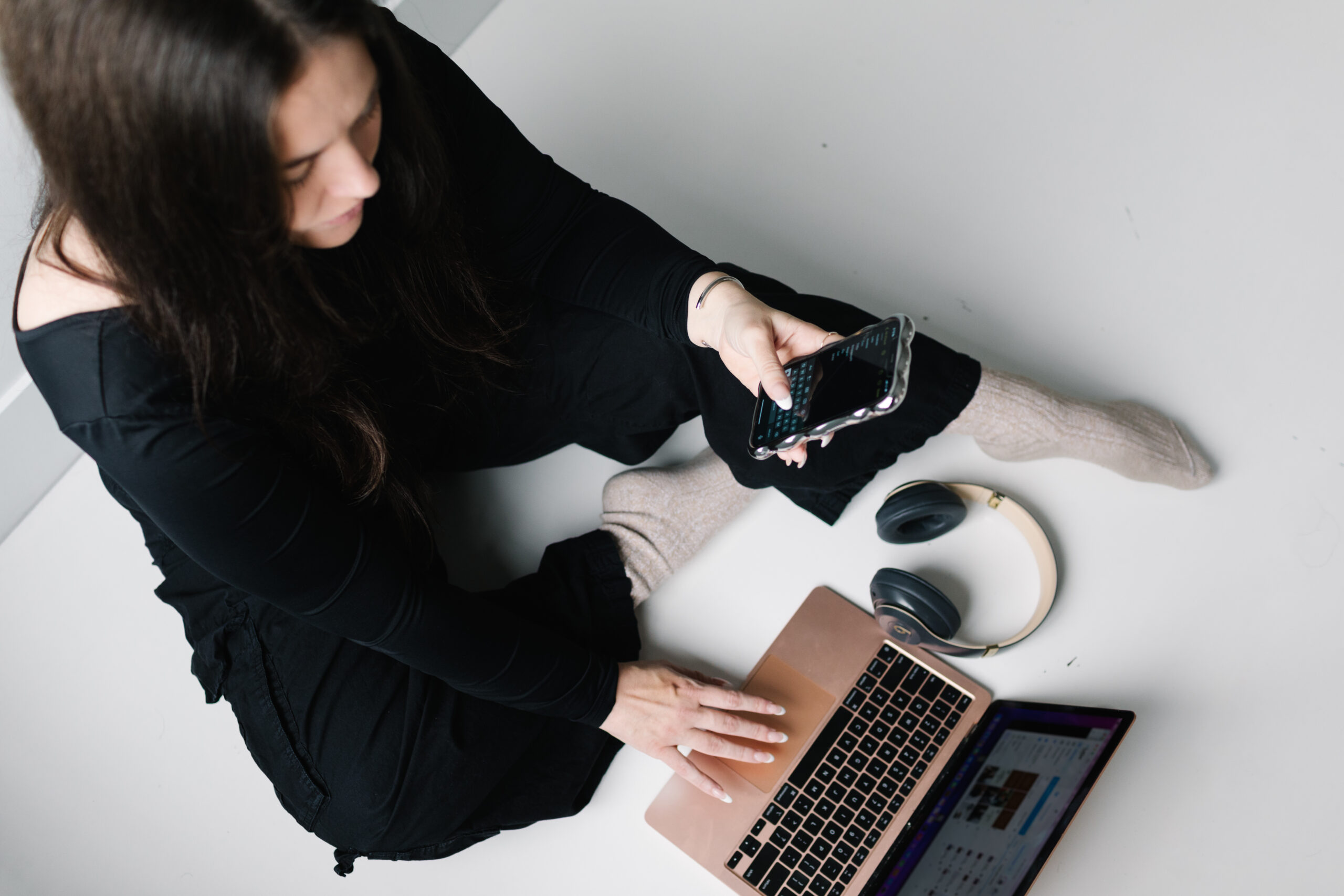 woman on her laptop with her phone and headphones | carlisledigitalmarketing.com